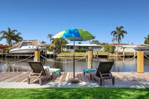 two chairs and an umbrella on a dock with a boat at Waterfront Fll&beaches, Bbq, Kayaks, Canoe in Dania Beach