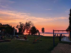a park with a playground with people and the water at Molnár Vendégház in Balatonboglár