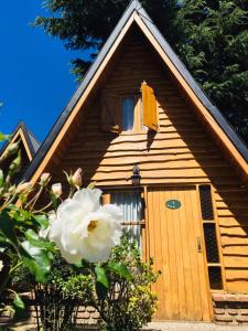 una casa con una flor blanca delante de ella en Cabañas Chapelco en San Martín de los Andes