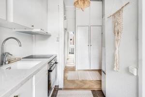 a kitchen with white cabinets and a hallway at WeHost Nordic Glamour nearby the Tervasaari Island in Helsinki