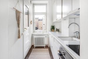 a white kitchen with a window and a radiator at WeHost Nordic Glamour nearby the Tervasaari Island in Helsinki