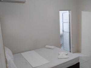 ein weißes Zimmer mit einem Bett und einem Spiegel in der Unterkunft Pousada e Hostel Sossego da Praia AJU in Aracaju