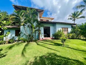 Espelho Bahia Blue House في برايا دو إسبيلهو: منزل مع ساحة خضراء مع أشجار النخيل