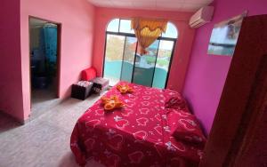 Habitación rosa con mesa y cama roja en La Casa de Jeimy en Puerto Baquerizo Moreno