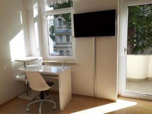 an office with a desk and a tv in a room at gemütliche kleine Ferienwohnung in Chemnitz