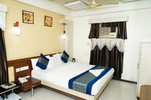 a bedroom with a bed and a desk and a window at Marshall The Hotel in Ahmedabad