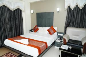 a hotel room with a bed and a chair at Marshall The Hotel in Ahmedabad