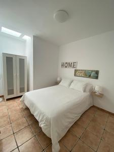 a bedroom with a white bed with a home sign on the wall at Apartamento Niar in Playa Honda
