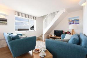 a living room with two blue chairs and a tv at St Ives Bay View in Carbis Bay