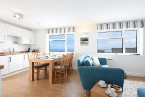 St Ives Bay View في Carbis Bay: مطبخ وغرفة معيشة مع طاولة وكراسي