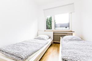 2 Betten in einem weißen Zimmer mit Fenster in der Unterkunft Apartment Köln Weidenpesch in Köln
