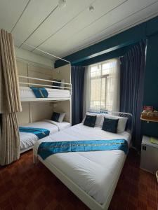 two beds in a room with blue walls at Acozyposhtel in Bangkok