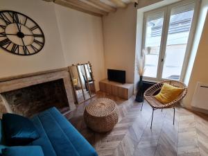 ein Wohnzimmer mit einem blauen Sofa und einer Uhr an der Wand in der Unterkunft Studio 2/4 personnes centre Bayeux in Bayeux