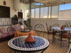 sala de estar con mesas, sillas y sofá en Dar Lalla Wafae, en Fez