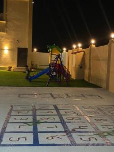 um parque infantil à noite com um sinal no chão em Almouj Chalet em Salalah