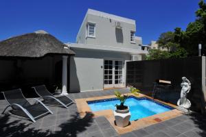 a villa with a swimming pool and a house at Little Scotia in Cape Town