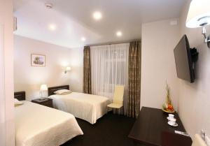 キーロフにあるHotel Classicのベッド2台とテレビが備わるホテルルームです。