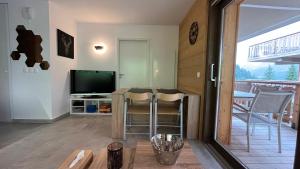 ein Wohnzimmer mit einem TV, einem Tisch und Stühlen in der Unterkunft Châtel - Appartement 4-6 personnes - Les Châlets des Freinets C203 in Châtel