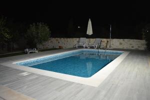 a swimming pool at night with two chairs and an umbrella at Casa da Pedra in Ancião