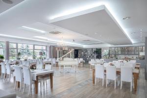 une salle à manger avec des tables et des chaises blanches dans l'établissement Hotel Europejski, à Nysa