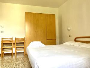 a bedroom with two beds and two chairs at Hotel Zanetti in Torri del Benaco