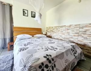 Schlafzimmer mit einem Bett mit einer schwarzen und weißen Bettdecke in der Unterkunft A l'ombre du goyavier in Le François