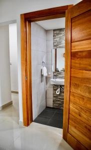 a bathroom with a sink and a wooden door at Super Luxurious L6 Sky Blue Apartment in Santo Domingo
