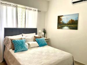 Schlafzimmer mit einem Bett mit blauen und weißen Kissen in der Unterkunft Super Luxurious L6 Sky Blue Apartment in Santo Domingo