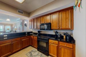 a kitchen with wooden cabinets and a stove top oven at Paradise Shores 105 in Mexico Beach