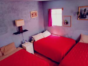 two beds in a room with red sheets and a window at Alo México in Mexico City