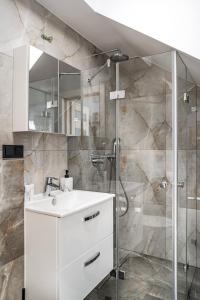 La salle de bains est pourvue d'un lavabo blanc et d'une douche. dans l'établissement Modrzewiowa Ostoja, à Kluszkowce