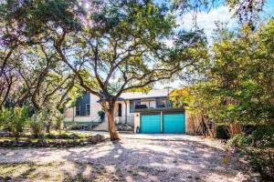 a house with a blue garage and a tree at Salt Water Pool & Backyard Oasis @ Wild Eagle in San Antonio