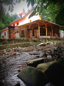 a building next to a river with rocks in front at Cabana de lângă Vale in Budureasa