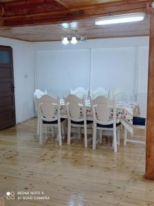 a dining room with white chairs and a table at Cabana de lângă Vale in Budureasa