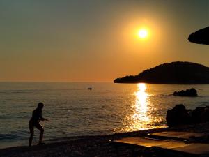 a person playing frisbee on the beach at sunset at Magic Ionian Apartments & Rooms in Himare