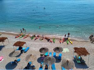 un grupo de personas en una playa con sillas y sombrillas en Magic Ionian Apartments & Rooms, en Himare