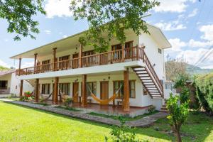 a large white house with a balcony at Hostería Paraíso in Vilcabamba