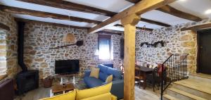 a living room with a blue couch and a stone wall at Casa Rural Carmen Luna in Miñera de Luna