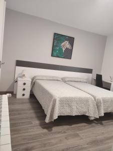 a white bedroom with a bed and a night stand at Casa Luzon, terraza-solarium con ducha y salon rustico in Villarejo de Salvanés