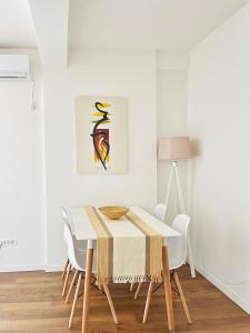 uma sala de jantar branca com uma mesa e cadeiras em Tower apartment em Pristina