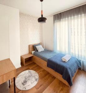 um quarto com uma cama e uma grande janela em Tower apartment em Pristina