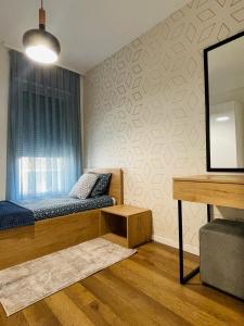 a bedroom with a bed and a desk and a mirror at Tower apartment in Prishtinë