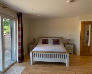 1 dormitorio con cama blanca y ventana en Plumptons Farm Holiday Lodges en Colchester