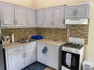 a kitchen with white cabinets and a stove and a sink at Cozy Studio Apartment in Quiet Neighborhood! in Philipsburg