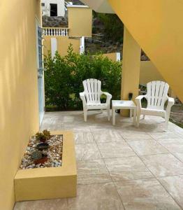 two white chairs sitting on a patio with a fountain at Cozy Studio Apartment in Quiet Neighborhood! in Philipsburg