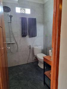 a bathroom with a toilet and a shower with blue towels at Suci's Friendly Appartment in Mataram