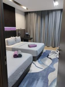 Habitación de hotel con 2 camas con almohadas moradas en Qing Yun Rest House Koprijaya, Brunei Darussalam en Bandar Seri Begawan