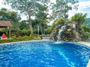 a swimming pool with a waterfall in a yard at Hostería Paraíso in Vilcabamba