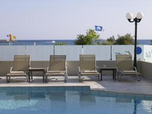 a group of chairs sitting next to a swimming pool at Kriti Beach Hotel in Rethymno Town