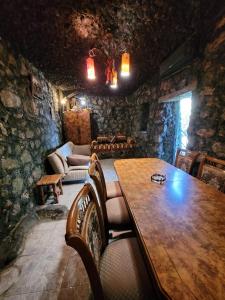 a dining room with a wooden table in a stone room at Holiday House in Yerevan with Garden and Lovely Views in Yerevan
